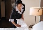 Professional staff. Nice serious hard working woman wearing a uniform and making the bed while working in the hotel